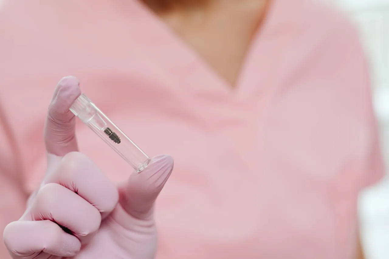 Dental professional holding a titanium implant post ready for surgical placement — the same Straumann system used at Taki Dent